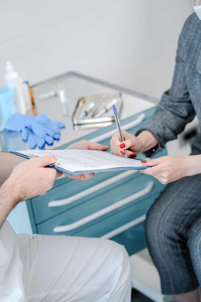 Patient signing healthcare agreement in doctor's office, focus on hands and document exchange.